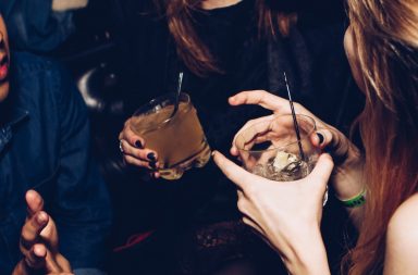 two women talking while holding drinking glasses